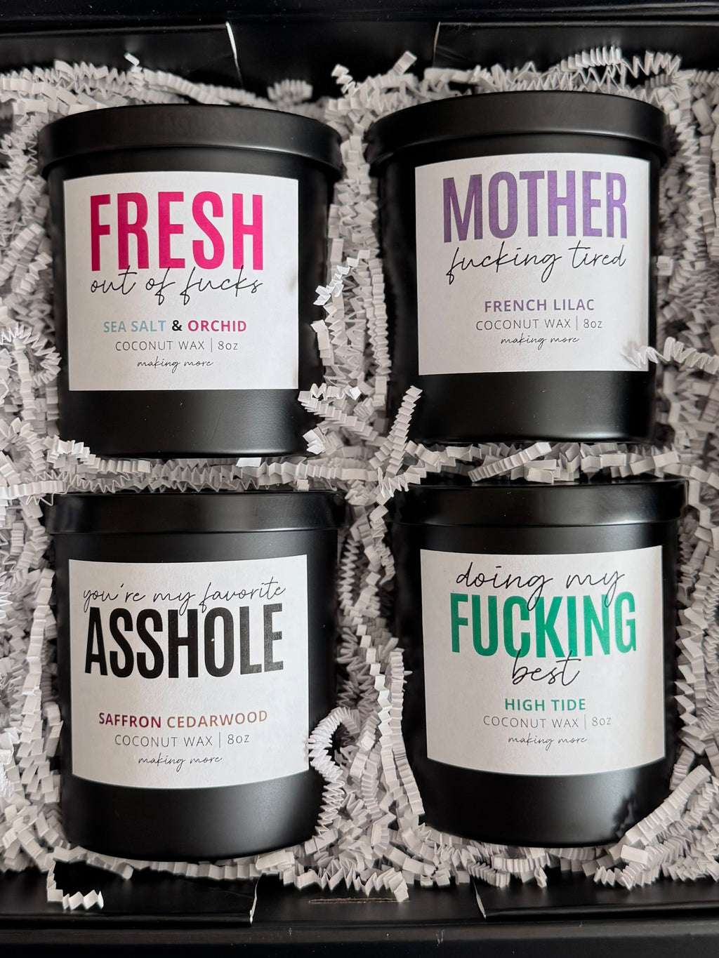 Four black candles with colorful labels in a decorative box.