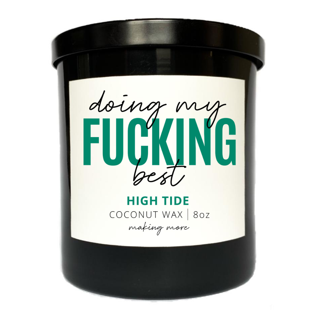 8 ounce coconut wax candle in a black glass jar. White label that says doing my fucking best. Fragrance is high tide.