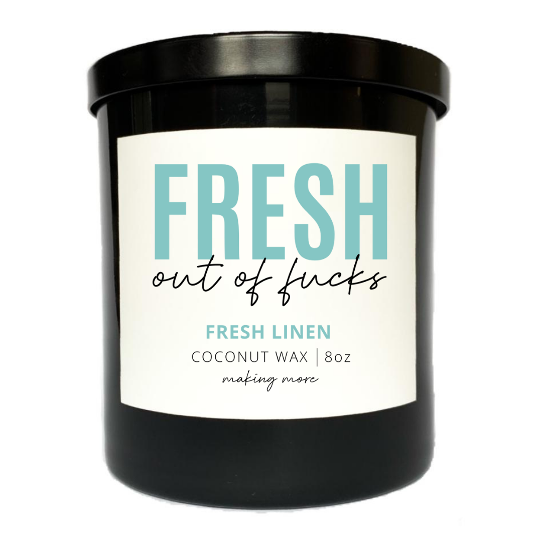 8 ounce coconut wax candle in a black glass jar. White label that says fresh out of fucks. Fragrance is fresh linen.